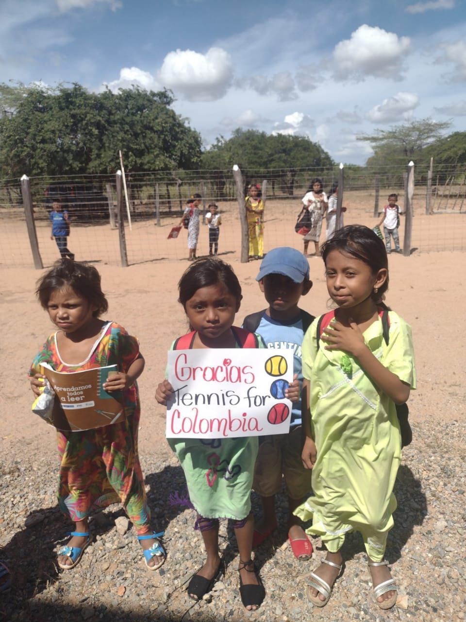 Niños beneficiarios sosteniendo cartel: Gracias Tennis For Colombia